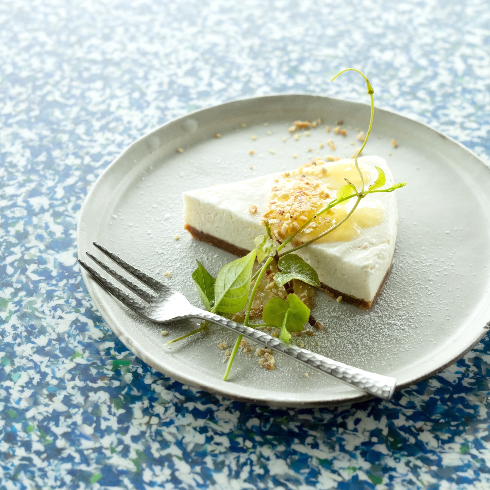 A minimalist overhead shot of a classic, moist chocolate cake slice on a handcrafted ceramic white plate. The setting is a clean, bright cafe table with subtle morning light. The styling is elegant and understated, emphasizing the rich texture of the cake and the clean lines of the pottery. High-key light-mode aesthetic.
